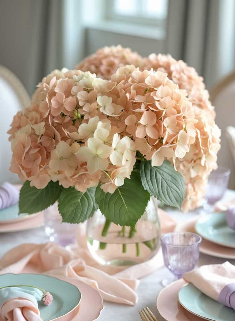 Vibrant pink and white hydrangea flower arrangement in a clear glass vase on a beautifully set dining table, perfect for elegant gatherings and wedding decor.
