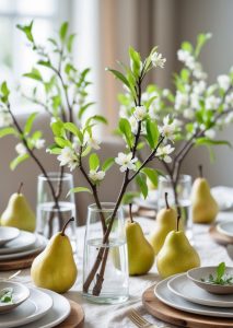 A dining table set with white plates, wooden chargers, and glasses holding budding branches, surrounded by fresh pears as decoration.