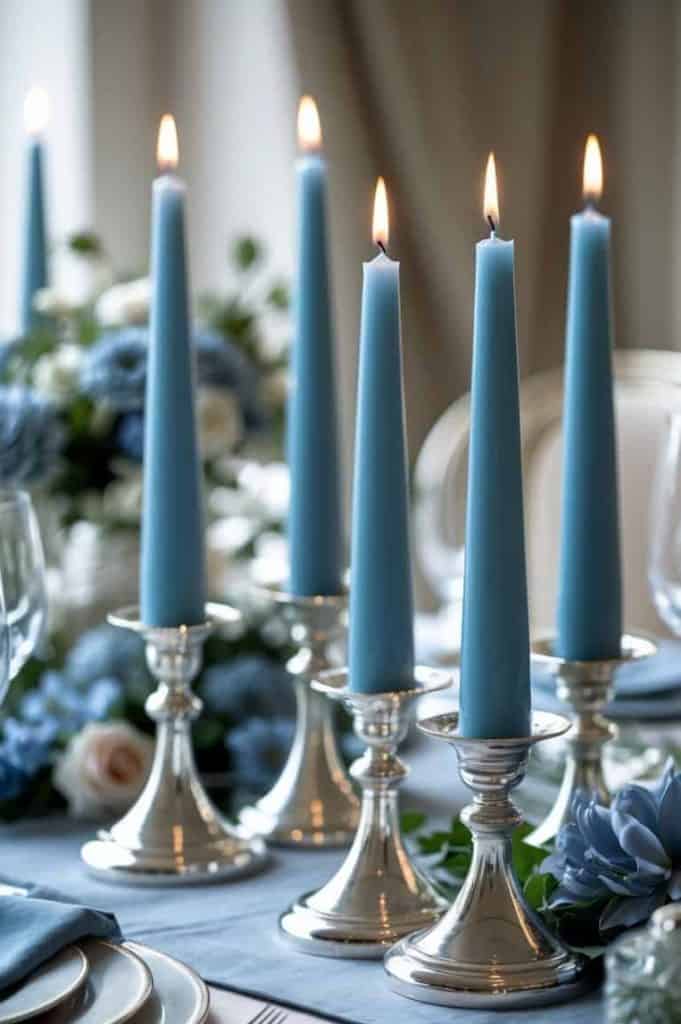 Silver candlesticks, tall, pale blue candles, soft blue linens, metallic accents, dusty blue and white flower arrangements, and gentle candlelight 