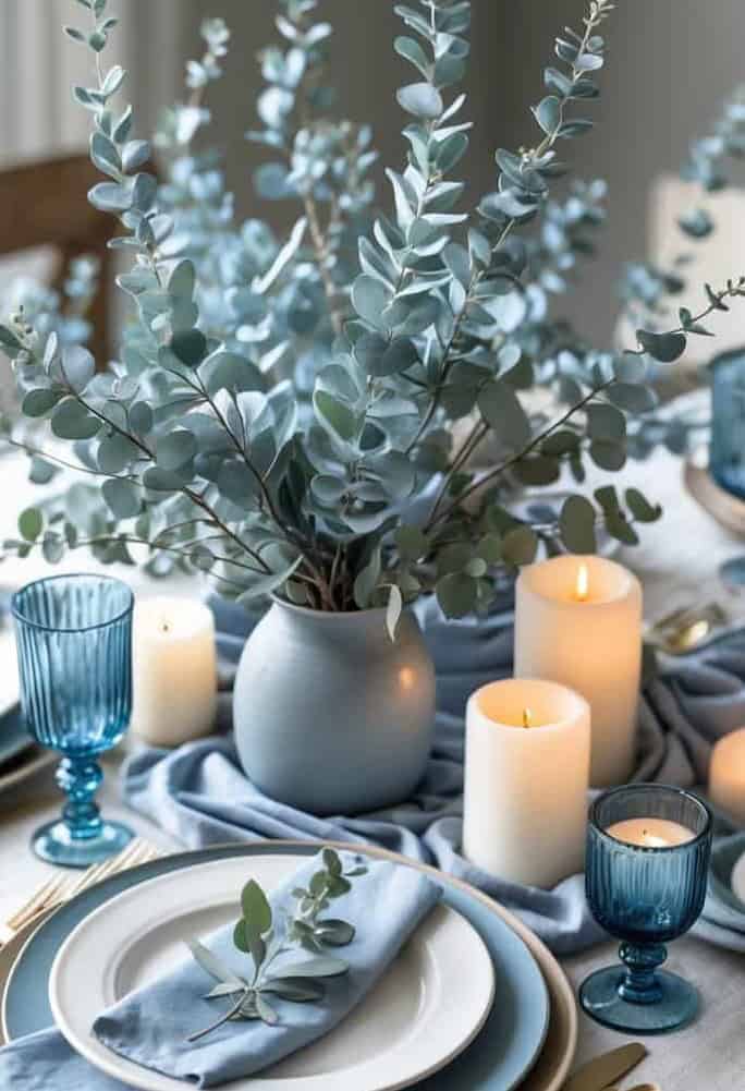 Dusty blue eucalyptus centerpiece with pillar candles and modern blue glassware