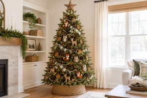 A woodland theme Christmas tree with fox, owl and deer ornaments, dried orange slices, pinecones and plaid ribbon in a woven basket collar, in a bright living room.